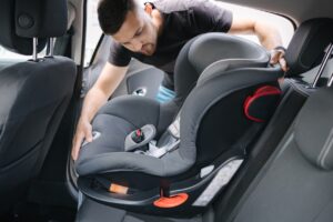 Man installing a child car seat in car at the back seat