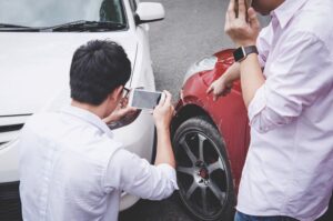 individuals taking photos of vehicle damage after a car accident
