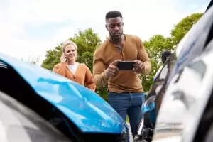 man taking photos of car damage after an accident while woman is on the phone