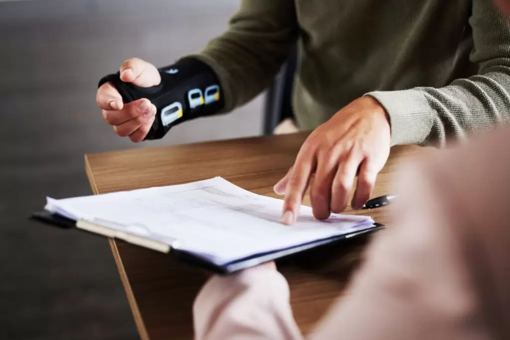 person with injured wrist pointing to legal document