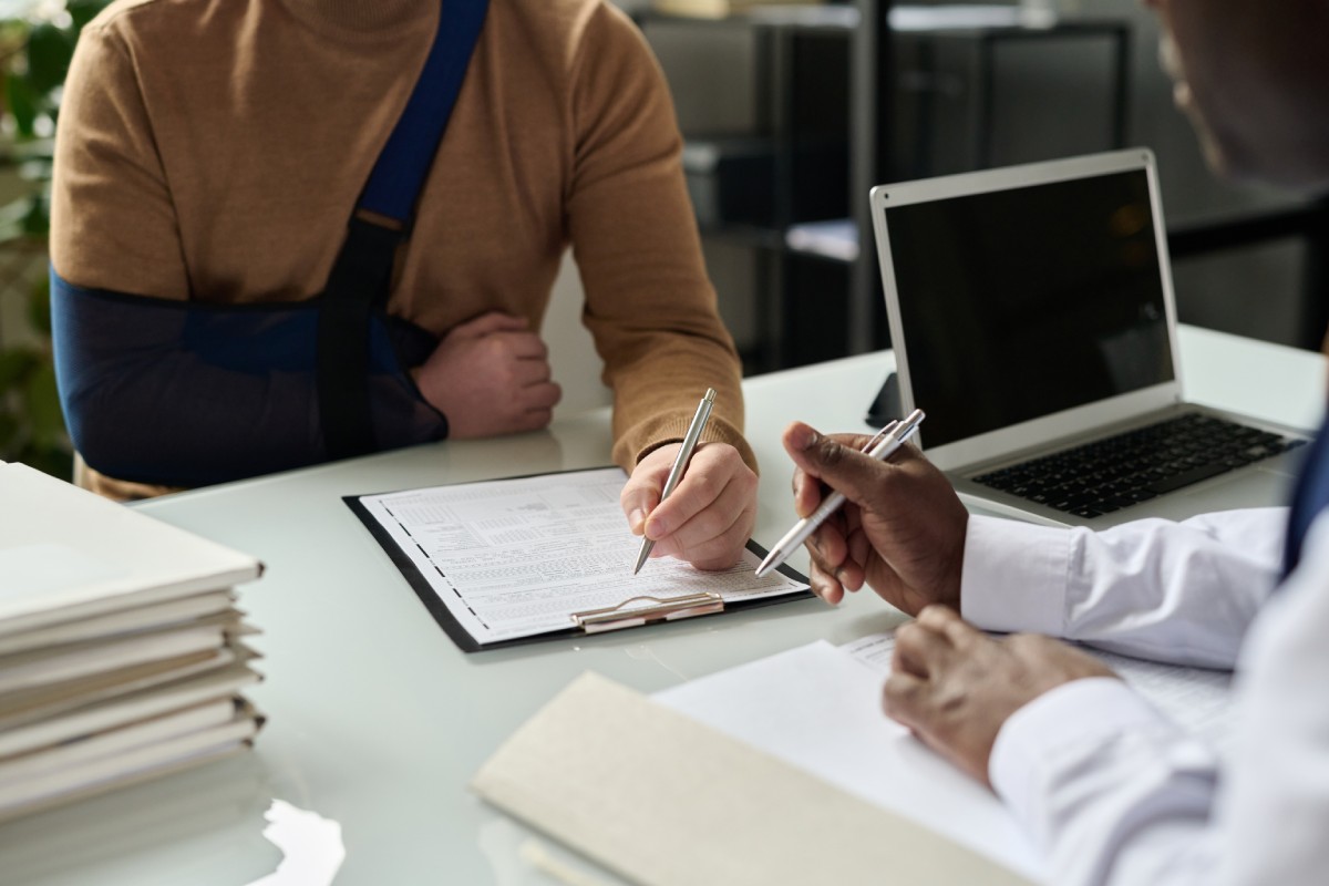injured person signing legal documents to recover compensation with the help of an attorney